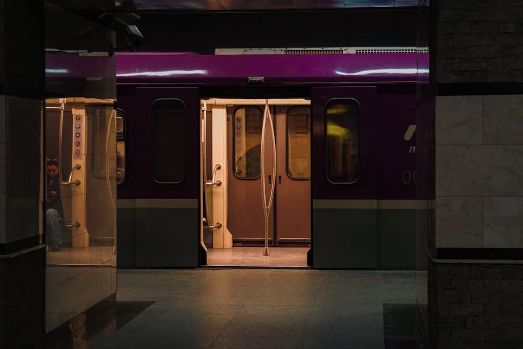 A subway train with open doors in a dark, urban underground metro station.